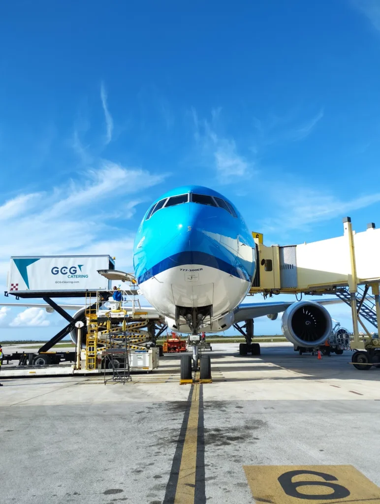 Aeronave en posición de abordaje con puente de embarque y equipo de rampa alrededor.
